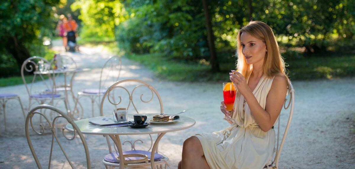 Slika dekleta v Ljubljani, ki sedi v lokalu in pije sok.